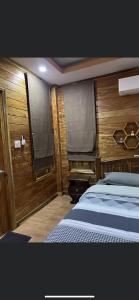 1 dormitorio con 1 cama y pared de madera en บ้านสวนรดา baansuanrada, en Ban Wang Hom