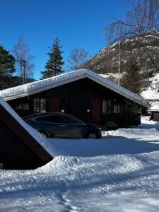 a car parked in front of a building in the snow at Enok Hytter & Resort in Liagardane