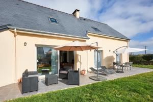 patio z krzesłami, stołem i parasolem w obiekcie Maison Ariel - Charmante maison pour 6 w mieście Bricqueville-sur-Mer