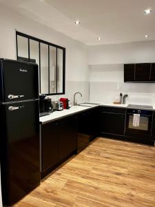 a kitchen with black cabinets and a black refrigerator at République :Appartement T3 Centre historique in Perpignan