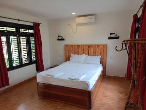 Schlafzimmer mit einem Bett mit weißer Bettwäsche und roten Vorhängen in der Unterkunft Tharu Lodge in Sauraha