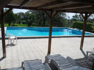 a swimming pool with chairs and a pavilion at Agriturismo Ruvitello in Misterbianco