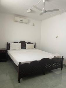 a bedroom with a bed with white sheets and a ceiling at Lavila beach cottage in Wadduwa