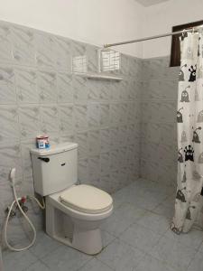 a bathroom with a toilet and a shower curtain at Lavila beach cottage in Wadduwa