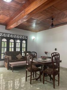 a dining room with a table and chairs and a couch at Lavila beach cottage in Wadduwa