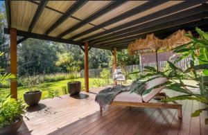 a wooden deck with a pergola with a bench on it at Jetty beach shack in Coffs Harbour