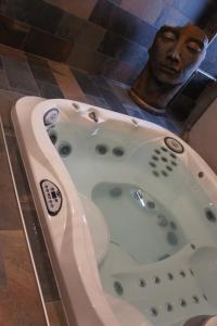 a bath tub with a statue of a man in a bathroom at L'espaco in Saint-Jeure-dʼAy