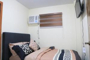 a bedroom with a bed and a window with a air conditioner at Anicia Guesthouse Rooms in Manila