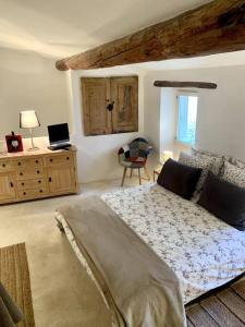 a bedroom with a bed and a desk with a laptop at La Petite Cave in Saignon