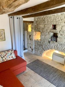 een woonkamer met een rode bank en een stenen muur bij La Petite Cave in Saignon
