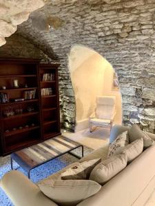 een woonkamer met een bank en een stenen muur bij La Petite Cave in Saignon