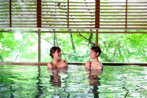 two people sitting in a swimming pool at Ooedo Onsen Monogatari Premium Kinugawa Kanko Hotel in Nikko