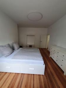 1 dormitorio con 1 cama blanca grande y suelo de madera en EG Weststadt Karlsruhe 4 Zimmer en Karlsruhe