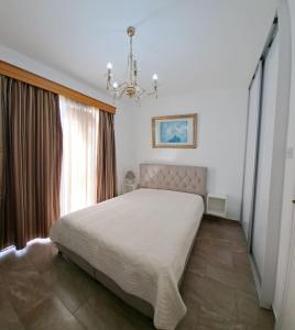 Un dormitorio con una cama grande y una lámpara de araña. en Isabella court Townhouse near Venus beach and Lidl, en Pafos