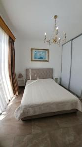 1 dormitorio con 1 cama con lámpara de araña y ventana en Isabella court Townhouse near Venus beach and Lidl, en Pafos