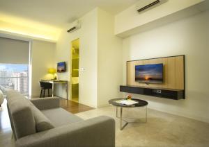 sala de estar con sofá y TV en la pared en The Signature Hotel & Serviced Suites Kuala Lumpur en Kuala Lumpur