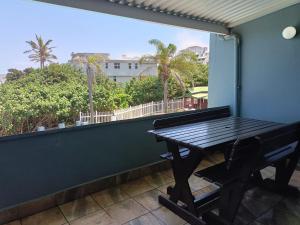 a patio with a table and a balcony with a view at Dumela Margate Flat No 12 in Margate