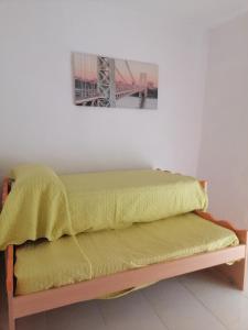 Una cama con una manta amarilla encima. en Almodovar Alojamientos en Almodóvar del Río