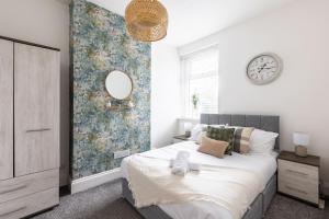 ein Schlafzimmer mit einem großen Bett und einem Spiegel in der Unterkunft Levi Suite by Koya Homes in Cardiff