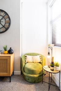 einen grünen Stuhl in einem Wohnzimmer mit einer Uhr in der Unterkunft Levi Suite by Koya Homes in Cardiff