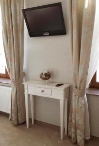 einen weißen Tisch mit einem TV an der Wand in der Unterkunft Prudentia Hotels Adler in Byczyna
