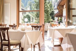 a restaurant with white tables and chairs and a window at Hotel Luna Mondschein in Ortisei