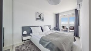 - une chambre blanche avec un lit et un balcon dans l'établissement Apartamenty Sun & Snow Rogowo Pearl, à Rogowo