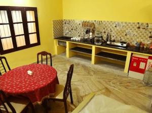 a dining room with a red table and a kitchen at Smith 5BHK Villa in Puducherry