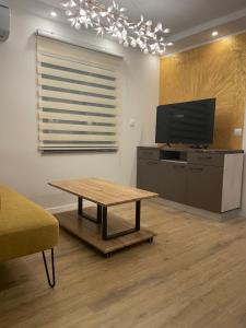 een woonkamer met een tafel en een flatscreen-tv bij Gold delux in Zagreb