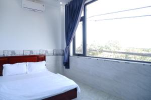 a bedroom with a bed and a large window at Thinh Khang Guesthouse in Buon Ma Thuot