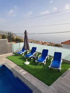 eine Terrasse mit Stühlen und Sonnenschirm und ein Pool in der Unterkunft Vila Castro in Estreito da Calheta