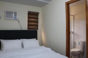 a bedroom with a white bed and a toilet at Anicia Guesthouse Units in Manila