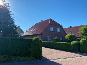 een stenen huis met heggen ervoor bij Ferien im Wangerland Ferienwohnung MUSCHEL Minsen Schillig Hund Pool Sauna in Wangerland