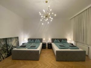 sala de estar con 2 camas y lámpara de araña en Apartments Opera, en Viena