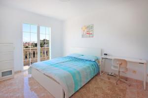 a bedroom with a bed and a desk and a window at Villa Domingos by Slow Villas in Calas de Mallorca