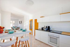 una cucina con mobili bianchi e sgabelli da bar di Villa Domingos by Slow Villas a Calas de Mallorca Altre 17 foto