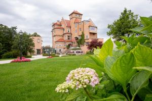 a large pink castle with green grass and flowers at Hotel Schloss Mönchstein in Salzburg