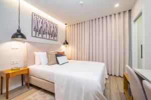 ein Schlafzimmer mit einem großen weißen Bett und einem Tisch in der Unterkunft Machim D'Arfet House by Madeira Sun Travel in Machico