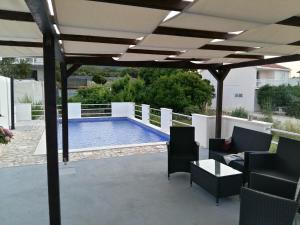 a pergola with chairs and a table and a swimming pool at Fei Fei Apartments 2 in Račišće