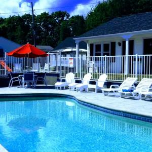a swimming pool with chairs and an umbrella at Carriage House Motel Cottages & Suites in Wells