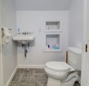 a white bathroom with a toilet and a sink at Carriage House Motel Cottages & Suites in Wells +35 photos