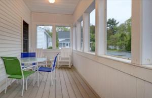 a porch with a table and chairs and windows at Carriage House Motel Cottages & Suites in Wells