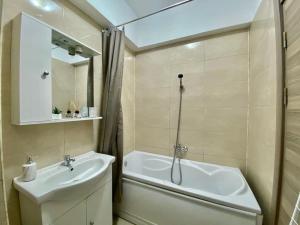 een badkamer met een wastafel, een bad en een spiegel bij Maria Summer Apartaments in Mamaia
