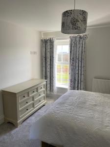 a bedroom with a bed and a dresser and a window at The Farmhouse in Swansea