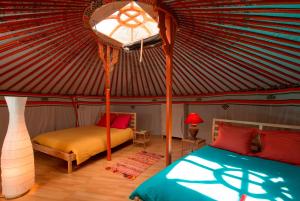 1 dormitorio con 1 yurta con 2 camas y 1 lámpara en Tiny House et yourte sous les Poiriers, en Domfront