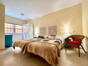 a bedroom with a large bed and a red chair at apartment in Villa de Mazo