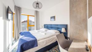 een slaapkamer met een bed, een bureau en een raam bij Apartamenty Sun & Snow Żeromskiego II in Hel