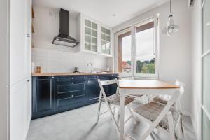 a kitchen with blue cabinets and a table and chairs at Ratibora Jurata, Sun & Snow in Jurata