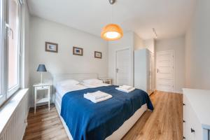 ユラタにあるApartamenty Sun & Snow Ratibora Jurataの白いベッドルーム(青いシーツとタオル付きのベッド付)