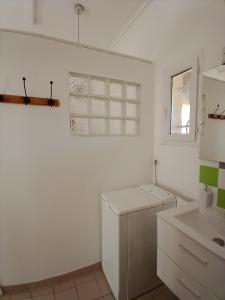eine weiße Küche mit einer Spüle und einem Kühlschrank in der Unterkunft Studio entre Aix et Marseille in Bouc-Bel-Air